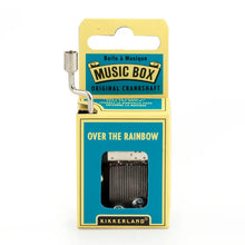 Load image into Gallery viewer, This image displays the bright teal and yellow cardboard packaging for a Kikkerland hand-crank music box, standing vertically against a plain white background. A silver metal crankshaft handle extends upward from the top left corner, while a small rectangular window on the front reveals the inner mechanical music parts directly beneath the printed song title, "OVER THE RAINBOW."