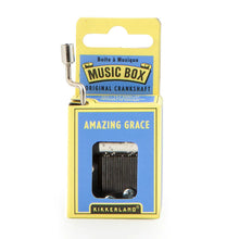 Load image into Gallery viewer, This image displays the medium blue and yellow cardboard packaging for a Kikkerland hand-crank music box, standing vertically against a plain white background. A silver metal crankshaft handle extends upward from the top left corner, while a small rectangular window on the front reveals the inner mechanical music parts directly beneath the printed song title, "AMAZING GRACE."