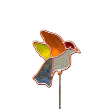 Load image into Gallery viewer, A single hummingbird-shaped plant stake. Crafted in a stained-glass style with a copper-toned border, the bird features texturized, translucent glass panels in orange, yellow and blue tail, a clear patterned belly, and red patch on its head.