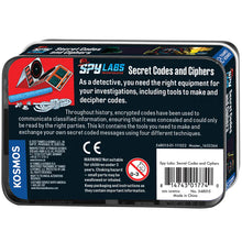Load image into Gallery viewer, This image shows the back of the "Secret Codes and Ciphers" rectangular tin storage box, featuring a dark blue background with educational text about encrypted messages, a barcode, and standard safety warnings. On the far left, a bright red panel showcases a clean illustration of the kit's actual tools, displaying the folded paper code ciphers standing upright above the blue wax crayon and the bundled hank of white string.
