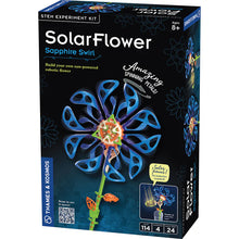 Load image into Gallery viewer, This image shows the packaging box for an engineering construction kit called "SolarFlower Sapphire Swirl," designed for ages 8 and up by Thames & Kosmos. The box features a dark background dominated by a large graphic of a sun-powered mechanical flower with sweeping, looped blue plastic petals that spin around an intricate hub of white, green, and orange gears attached to a long green stem.