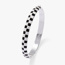 Load image into Gallery viewer, A silver hinged bangle bracelet by Alex and Ani shown closed and upright, showcasing the smooth, polished inner surface and the checkered black-and-white enamel outer band.