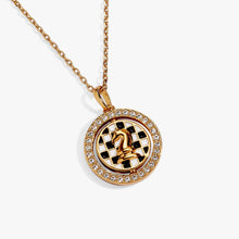 Load image into Gallery viewer, Close-up view of the gold necklace pendant showing a crystal-lined outer ring with a spinning center that displays a gold knight chess piece against a black-and-white checkered backdrop.