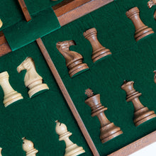Load image into Gallery viewer, A close-up view shows light and dark wooden chess pieces resting in custom slots within a green felt-lined storage case.