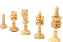 Load image into Gallery viewer, A close-up, angled view showing light-colored, intricately hand-carved wooden chess pieces with delicate pierced details arranged in a row against a white background.