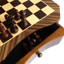 Load image into Gallery viewer, A close-up view of dark carved wooden chess pieces on a contoured wooden chessboard with an open built-in side drawer.