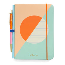 Load image into Gallery viewer, This image features the "Lined Mini Notebook & Pen" set shown from the front with its retail bellyband removed. The hardcover journal is decorated with a modern, pastel-colored geometric background split diagonally between peach and teal, centered by a large orange and white circular design. A bright orange elastic band secures the book vertically, while a slim orange and pink color-blocked pen is held snugly in place along the spine by a dark blue loop.
