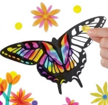 Load image into Gallery viewer, This close-up image of a person's fingers pressing a translucent yellow sticker onto the large, bold black outline of a butterfly's wing. While the left side of the butterfly is filled with vibrant, stained-glass-like patterns of rainbow colors, the right side remains mostly empty white space, surrounded by a few bright pink and yellow floral accents.