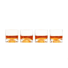 Load image into Gallery viewer, A line of four clear tumbler glasses, each filled with amber whiskey submerged around raised 3D glass mountain peaks at the base.