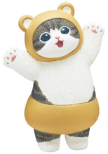 Load image into Gallery viewer, A grey-and-white tabby cat figurine standing against a plain white background, wearing a mustard-yellow bear costume with small rounded ears and matching shorts. The cat has a open-mouthed expression and stands with both arms raised in a wave, showing off its pink paw pads.
