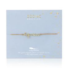 Load image into Gallery viewer, This image shows a gold "Aquarius" script bracelet mounted flat against a light, dusty-blue square card featuring metallic gold star decorations. The dainty bracelet consists of an adjustable tan cord threaded through a small, delicate cursive nameplate charm dipped in 14k gold.