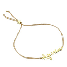 Load image into Gallery viewer, This image shows the unboxed "Aquarius" bracelet arranged in a loose loop against a plain white background. The delicate cursive gold nameplate rests at the bottom, while the double-strand tan cord threads through a tiny, metallic gold star-shaped slider at the top to adjust the fit.