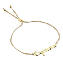Load image into Gallery viewer, This image shows the unboxed "Capricorn" bracelet arranged in a loose loop against a plain white background. The delicate cursive gold nameplate rests at the bottom, while the double-strand tan cord threads through a tiny, metallic gold star-shaped slider at the top to adjust the fit.