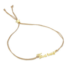 Load image into Gallery viewer, This image shows the unboxed "Taurus" bracelet arranged in a loose loop against a plain white background. The delicate cursive gold nameplate rests at the bottom, while the double-strand tan cord threads through a tiny, metallic gold star-shaped slider at the top to adjust the fit.