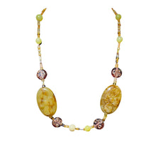 Load image into Gallery viewer, This handcrafted necklace features two large carved floral oval amber beads symmetrically accented by patterned round bronze-toned beads, pale yellow spherical stones, and tiny seed beads.