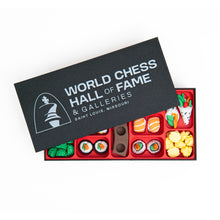 Load image into Gallery viewer, A black box labeled "World Chess Hall of Fame & Galleries" sits partially open, revealing a bright red bento-style organizer filled with colorful sushi-themed chess pieces.