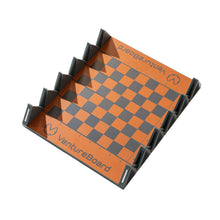 Load image into Gallery viewer, An angled overhead view of an empty, unfolded VentureBoard mini travel chess board showcasing its orange-and-grey grid and grey plastic folding frame.
