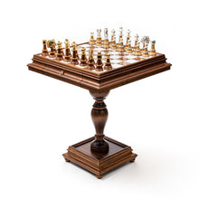 Load image into Gallery viewer, A full view of a wooden pedestal chess table set with dark and light metallic-trimmed chess pieces against a plain white background.