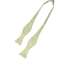Load image into Gallery viewer, This is an untied sage green bow tie featuring a subtle, metallic gold print of intricate, vintage-style chess pieces running along the length of its ends.