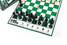 Load image into Gallery viewer, A close-up view of a green and white Bobby Fischer learn-to-play chessboard showing black pieces arranged along the edge above printed rules explaining move directions for each piece.
