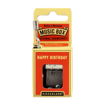 Load image into Gallery viewer, This image displays the bright red and yellow cardboard packaging for a Kikkerland hand-crank music box, standing vertically against a plain white background. A silver metal crankshaft handle extends upward from the top left corner, while a small rectangular window on the front reveals the inner mechanical music parts directly beneath the printed song title, "HAPPY BIRTHDAY."
