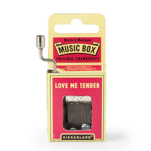 Load image into Gallery viewer, This image displays the same style of small, hand-cranked music box, this time packaged with a crimson red and pale yellow cardboard design. A silver metal crank curves up from the top left corner, and the front red panel clearly shows the text "LOVE ME TENDER" just above the cutout window exposing the internal metal gears.
