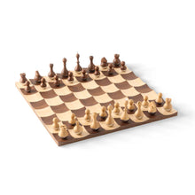Load image into Gallery viewer, Angled perspective view of the Umbra Wobble Wooden Chess Set, featuring a undulating concave grid board made of light maple and dark walnut wood with matching wooden pieces balanced on weighted, rounded bases.
