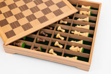 Load image into Gallery viewer, A wooden chessboard top partially lifted to reveal built-in storage compartments filled with individual chess pieces inside the base.
