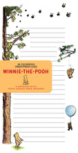 Load image into Gallery viewer, A lined notepad page features classic Winnie-the-Pooh illustrations of Pooh bear floating with a balloon and standing near a tall tree, partially wrapped with a yellow branded cover band.
