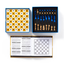 Load image into Gallery viewer, A complete chess game set laid out flat showing the perforated board, custom black foam piece tray holding blue and natural wood peg pieces, and an open instruction guide.
