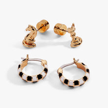Load image into Gallery viewer, A four-piece gold earring set featuring a pair of stud earrings shaped like a chess knight and rook alongside a pair of small hoop earrings detailed with black-and-white enamel checkerboard pattern.

