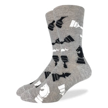 Load image into Gallery viewer,  A pair of grey crew-length socks displayed side-by-side against a plain white background. The fabric is patterned with stylized, graphic silhouettes of black and white chess pieces, including knights, rooks, kings, and pawns, scattered across the entire surface.
