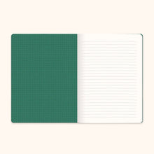 Load image into Gallery viewer, an open notebook is lying flat against a light cream-colored background, revealing its inner left and right pages. The left inside cover is a solid forest green color featuring a subtle grid pattern of thin, dark intersecting lines, while the right page is crisp white with standard, light-blue horizontal writing lines.
