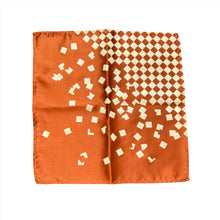 Load image into Gallery viewer, This is a copper-orange pocket square with a cream-colored checkered design in the top-right corner that fragments into floating geometric squares.
