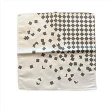Load image into Gallery viewer, This is an off-white pocket square featuring a charcoal grey checkered pattern in the upper-right corner that breaks apart into floating square accents across the fabric.
