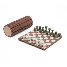Load image into Gallery viewer, A forest-themed chess set with mushroom-shaped pieces is set up on a brown-and-white segmented board next to its textured, log-shaped storage container.
