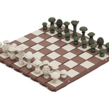 Load image into Gallery viewer, An angled overhead view shows a complete chess set with off-white and forest green mushroom pieces placed on a brown-and-tan segmented board.
