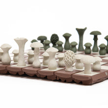 Load image into Gallery viewer, A low-angle close-up showcases off-white and dark green mushroom-shaped pieces lined up on a brown, segmented board.
