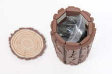 Load image into Gallery viewer, A top-down view shows the interior of the hollow log container holding bagged game pieces alongside its detachable wood-grain end cap.
