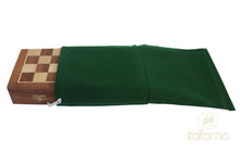 Load image into Gallery viewer, A folded wooden chessboard being inserted into a dark green felt drawstring storage bag.
