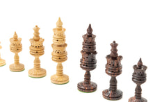 Load image into Gallery viewer, An angled perspective displaying light and dark hand-carved wooden chess pieces featuring elaborate layered and perforated designs set against a plain white background.
