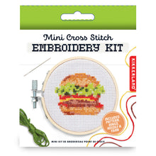 Load image into Gallery viewer, This retail box for the Kikkerland "Mini Cross Stitch Embroidery Kit" features a food-themed design topped with a bright green hanging tab. The clean white packaging prominently displays an illustration of a completed cross-stitch project showcasing a layered, multi-colored cheeseburger framed inside a tiny wooden hoop.
