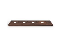 Load image into Gallery viewer, This is a long, rectangular tasting flight board made of a smooth wood with a dark brown, visible grain. It features four circular, shallowly recessed slots carved in a row along its surface, each with a small white hole cut out directly in the center to hold tasting glasses. It is lit from the bottom in each recess. 
