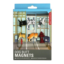 Load image into Gallery viewer, retail packaging for "Dog Butt Magnets" presented in a light blue cardboard box with a large cutout window displaying a city street backdrop. Inside the window, five detailed, three-dimensional plastic dog rears—including a spotted Dalmatian, a grey poodle, and a golden retriever—are arranged alongside a tiny red fire hydrant.
