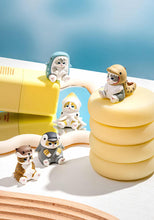 Load image into Gallery viewer, Five small cat figurines in marine animal costumes arranged across a white surface against a soft blue gradient background. Some figures sit directly on the tabletop, while others are perched atop yellow cosmetic containers, a stack of soft pastel yellow discs, and beside a small mirror reflection.
