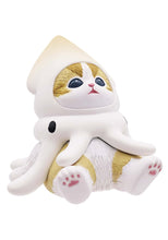 Load image into Gallery viewer, A small ginger-and-white cat figurine sitting against a plain white background, wearing a cream-colored squid costume. The costume features a pointed hood over the cat's head, with  squid tentacles draping down around its chest and sides while its white paw pads face forward. 
