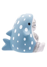 Load image into Gallery viewer, A side-profile of the grey tabby cat figurine sitting on a white background wearing its light blue, white-polka-dotted whale shark suit. The costume features a small side fin, a dorsal fin on the back, and a notched tail fin sticking out behind the seated cat.
