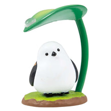 Load image into Gallery viewer, A small, round white long-tailed tit figurine with black-and-tan wings, standing on a grassy base against a plain white background. It perches under a tall green stem that curves over its head like an umbrella, complete with a broad leaf holding a single, clear raindrop. 
