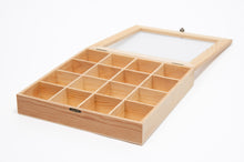 Load image into Gallery viewer, An open light wooden organizer box with sixteen equal compartments and a hinged glass-top lid lying flat behind it.
