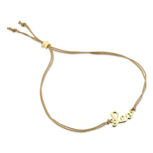 Load image into Gallery viewer, This image shows the unboxed "Leo" bracelet arranged in a loose loop against a plain white background. The delicate cursive gold nameplate rests at the bottom, while the double-strand tan cord threads through a tiny, metallic gold star-shaped slider at the top to adjust the fit.
